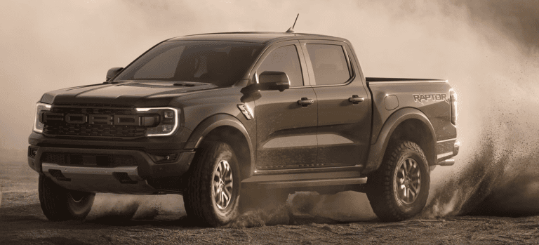 green ford ranger truck driving through dirt